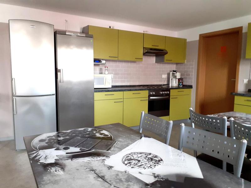 eine Küche mit einem Tisch, gelben Schränken und einem Kühlschrank in der Unterkunft Pension BERLIN in Spremberg in Spremberg