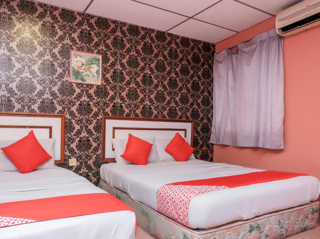 2 łóżka w pokoju z czerwonymi poduszkami w obiekcie OYO 90167 Hotel Tiara w mieście Kampong Kemaman