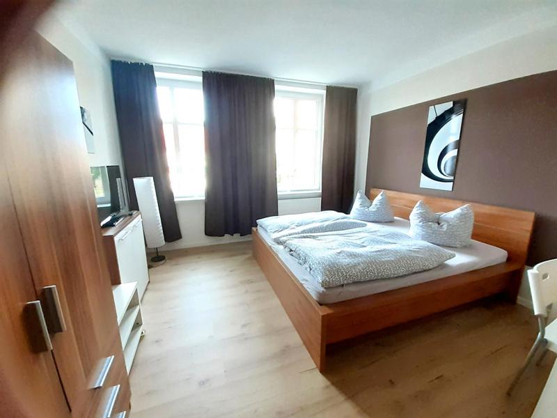 Schlafzimmer mit einem Bett mit weißer Bettwäsche und Kissen in der Unterkunft Pension BERLIN in Spremberg in Spremberg