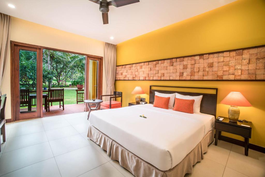 a bedroom with a large bed and a patio at Pandanus Resort in Mui Ne