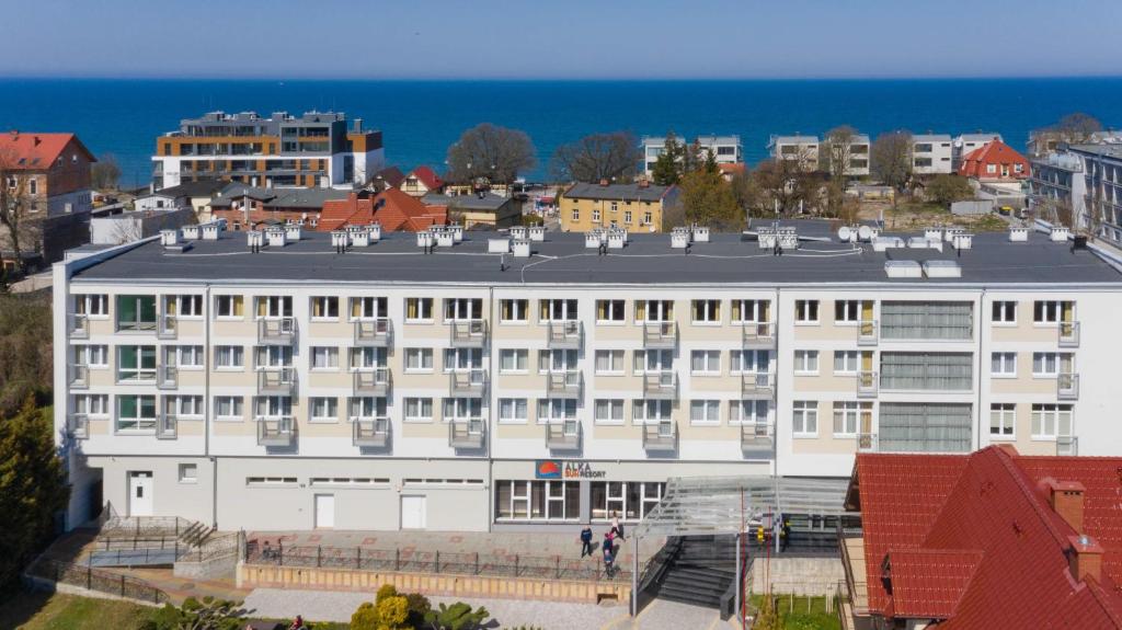 ein großes weißes Gebäude vor dem Meer in der Unterkunft ALKA Sun Resort in Ustronie Morskie