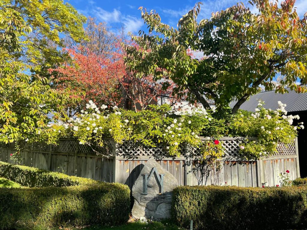 a statue in a garden in front of a fence at Arrowtown House Boutique Hotel in Arrowtown