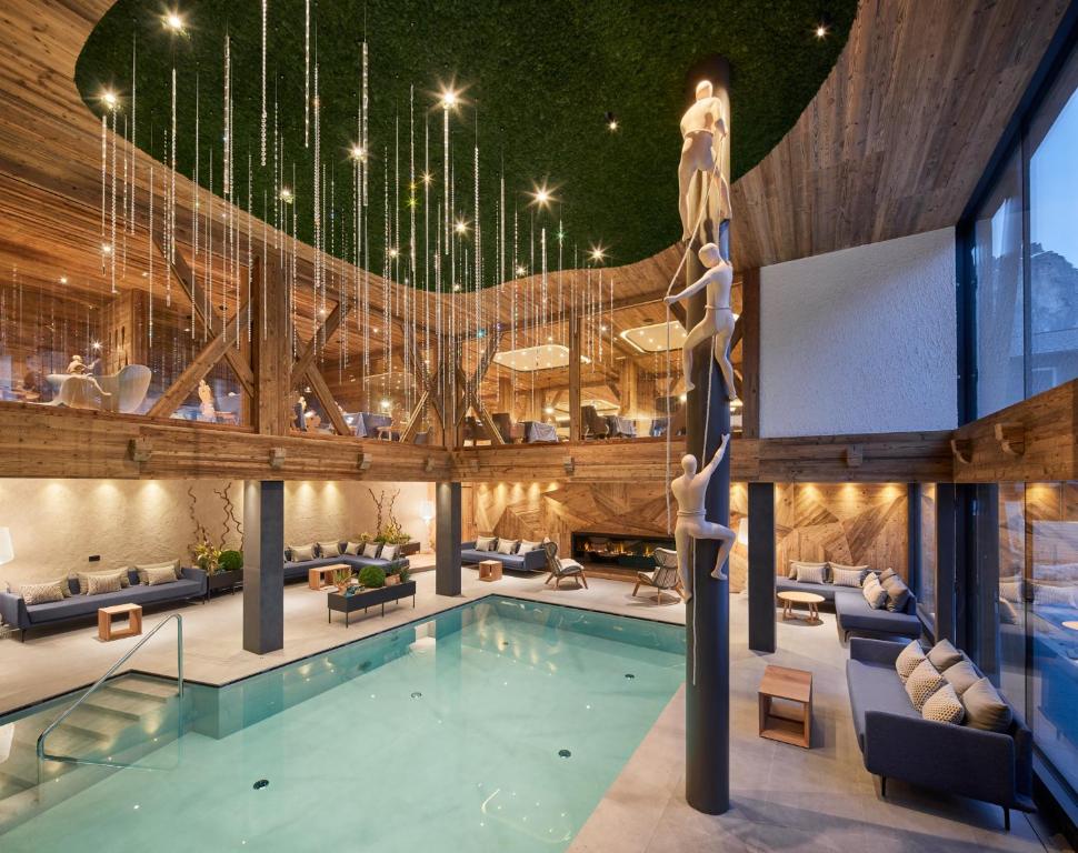 una piscina nella hall dell'hotel con un grande soffitto di Hotel Marmolada a Corvara in Badia