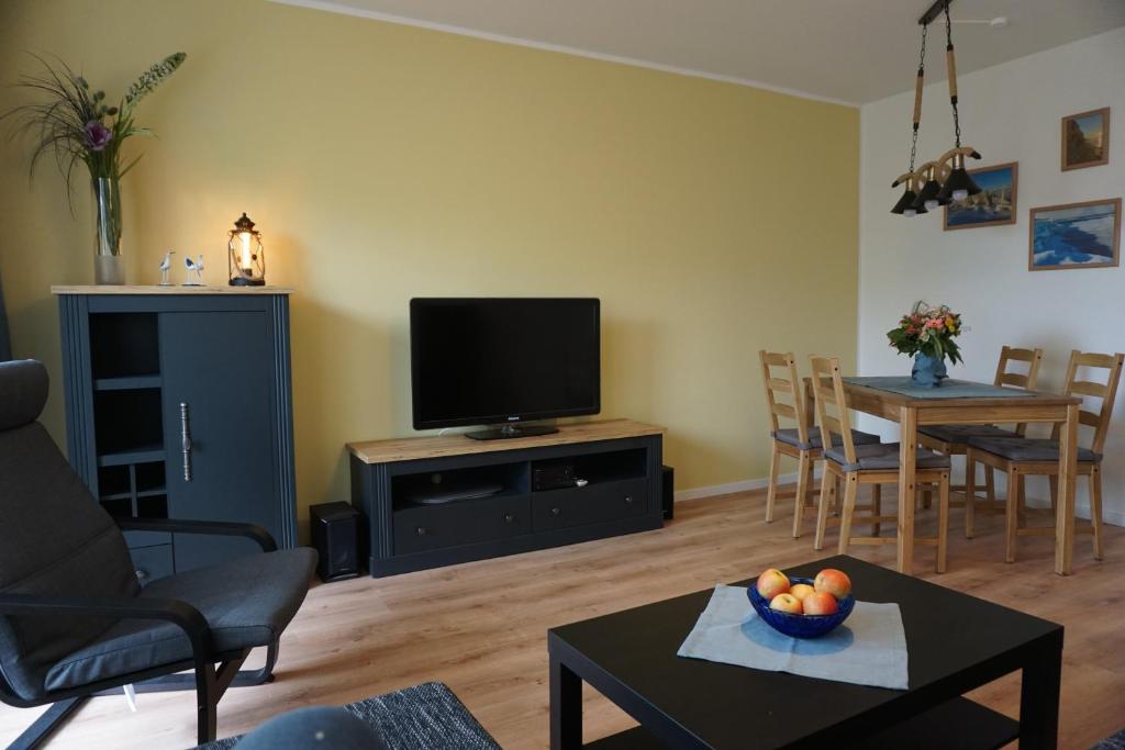 ein Wohnzimmer mit einem TV und einem Tisch mit einer Obstschale in der Unterkunft MeerZeit-Sellin in Ostseebad Sellin