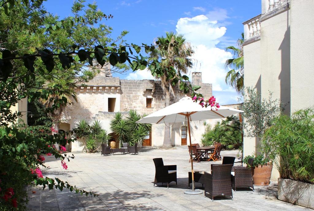 a patio with a table and an umbrella and chairs at Masseria Pagani in Nardò