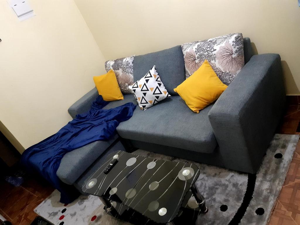 un sofá azul con almohadas en una habitación en Rubi Apartment, en Naivasha