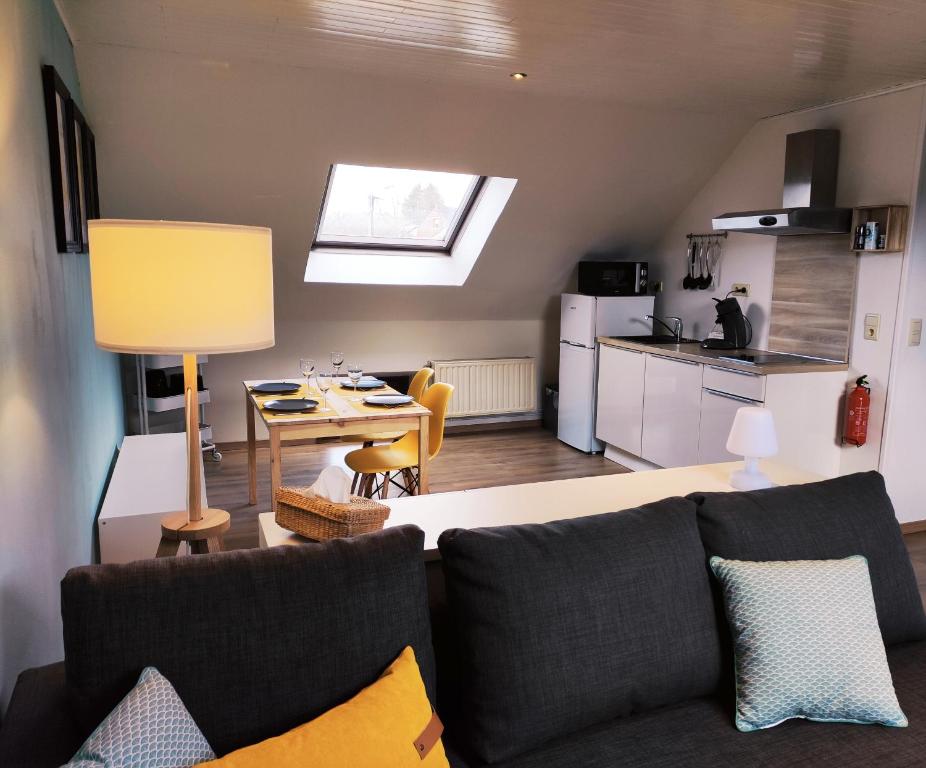 a living room with a couch and a table and a kitchen at Lacs de l'eau d'heure Chez Oma in Cerfontaine