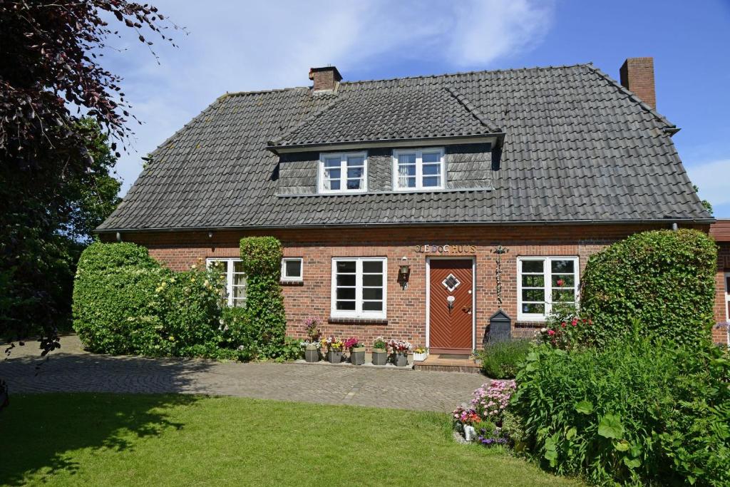ein rotes Backsteinhaus mit brauner Tür in der Unterkunft fewo1846 - De-ole-Doc-Hus - ehemaliges Landarzthaus mit großem Garten in Satrup