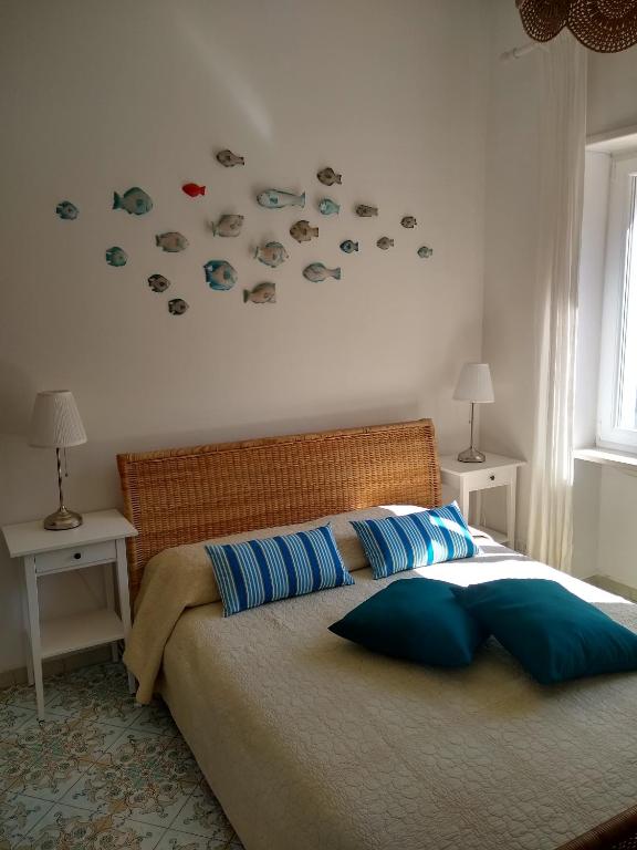 a bedroom with a bed with blue pillows and fish stickers on the wall at Soleluna in Capri