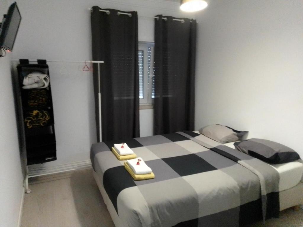 a bedroom with a bed with black and white sheets at GuestHouse Marialva Park in Corroios