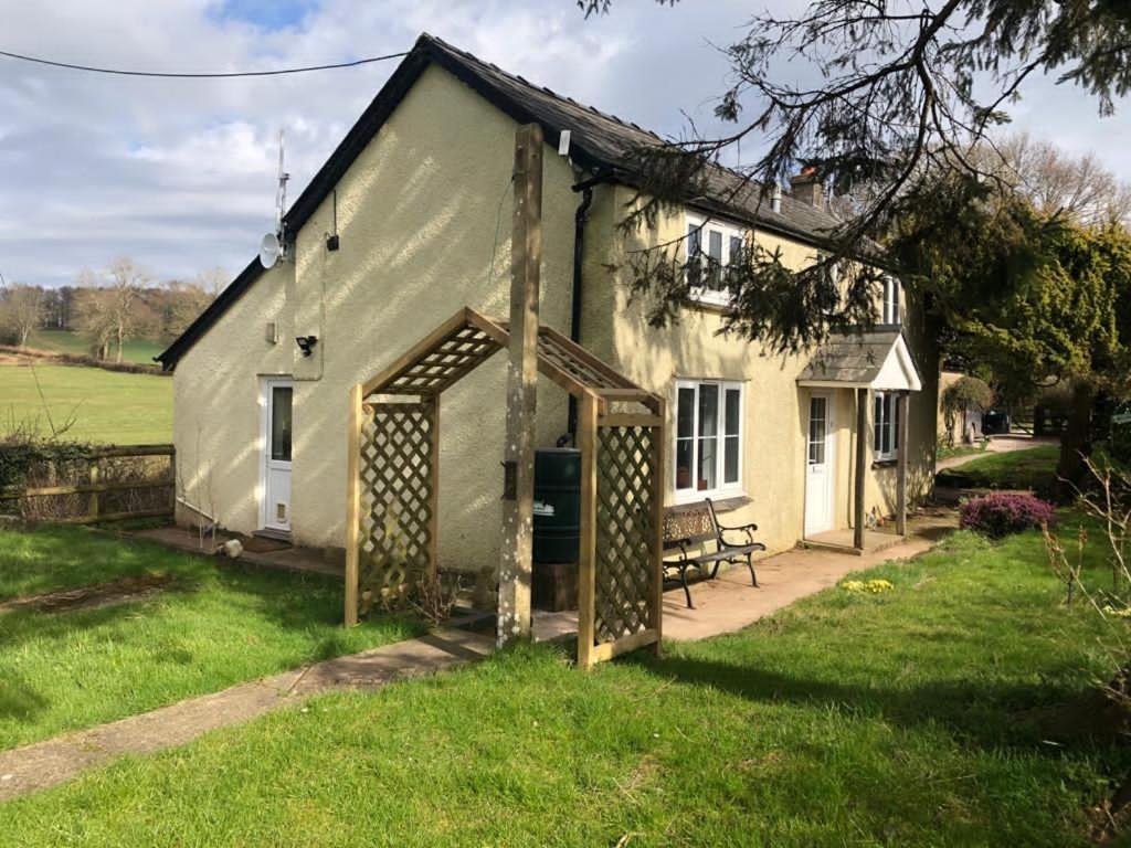 a white house with a bench in front of it at Hollybush cottage in Abergavenny