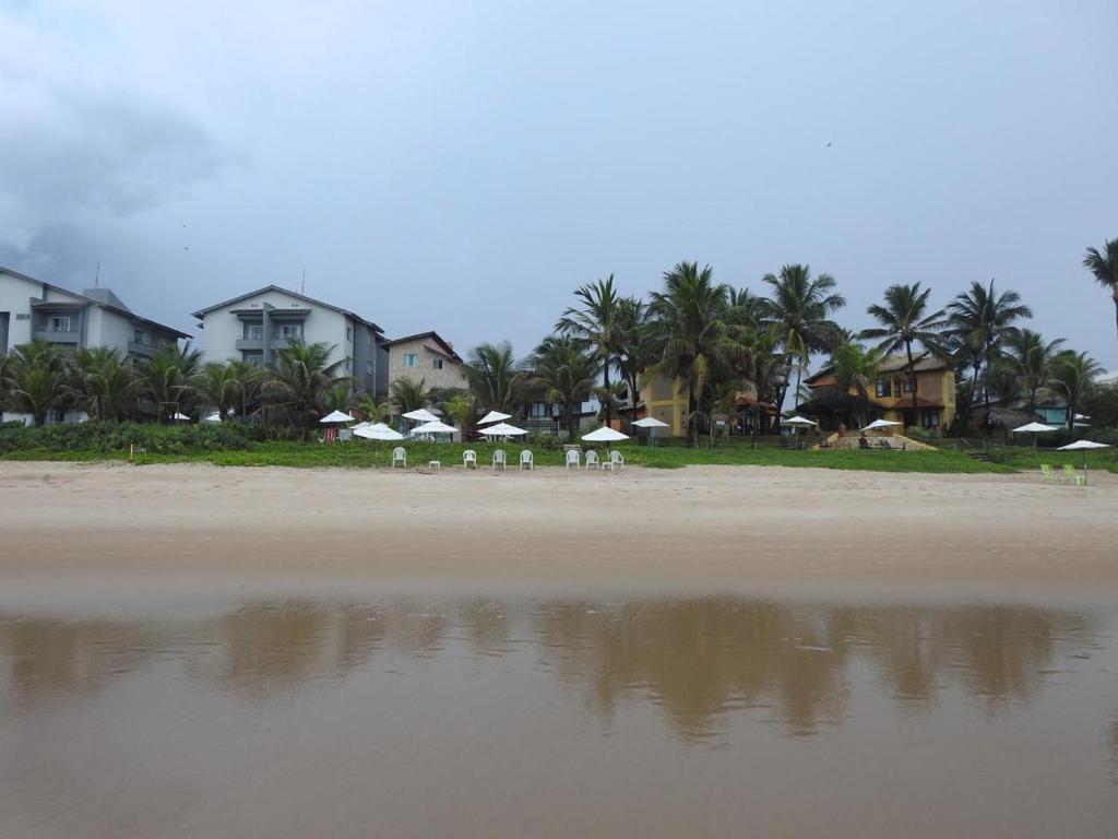 uma praia com algumas cadeiras e guarda-sóis e casas em Apartamentos beira mar em Porto de Galinhas