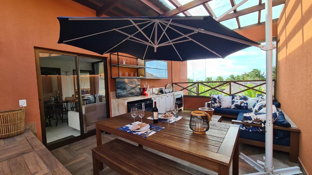 a dining room with a table and an umbrella at Belíssimo apartamento em Barra Grande Cobertura Villas BobZ 101 m2 com Vista Para o Mar, Barrinha, Barra Grande-PI in Barrinha