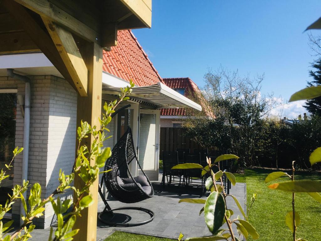 un porche de una casa con un banco en el patio en Bendalong Noordwijk, en Noordwijk