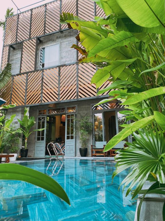 a house with a swimming pool in front of a building at Tropical Home Villa in Hoi An