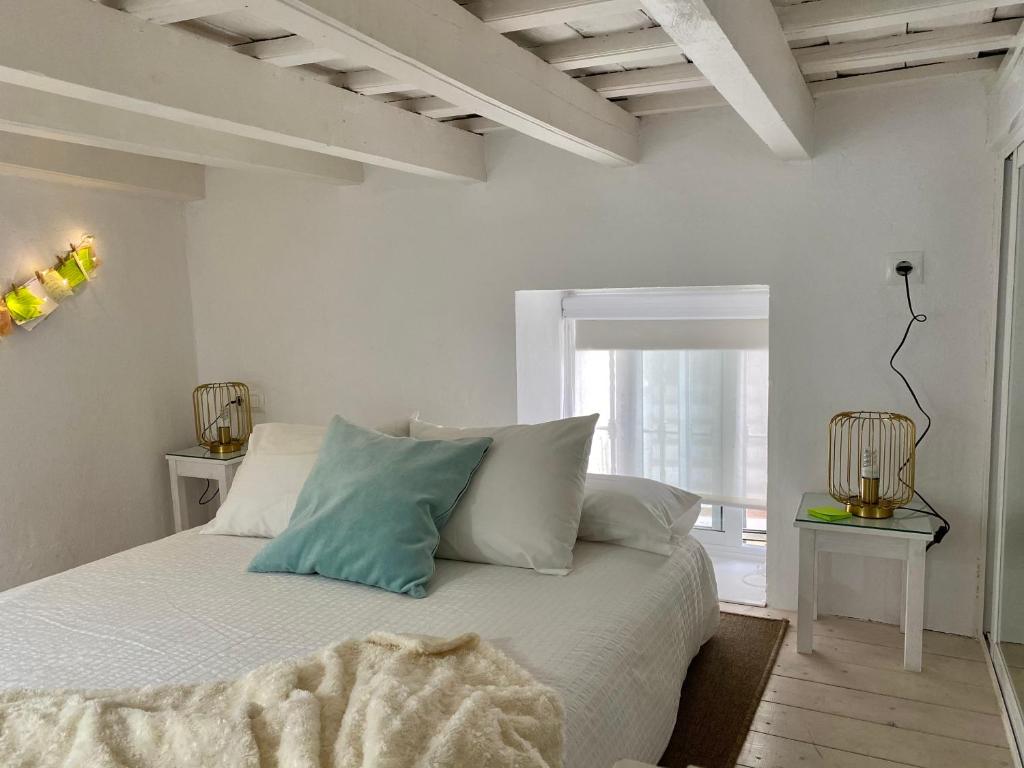 ein Schlafzimmer mit einem Bett mit weißen Laken und Kissen in der Unterkunft Casa Romántica "La CHELA" in Vejer de la Frontera
