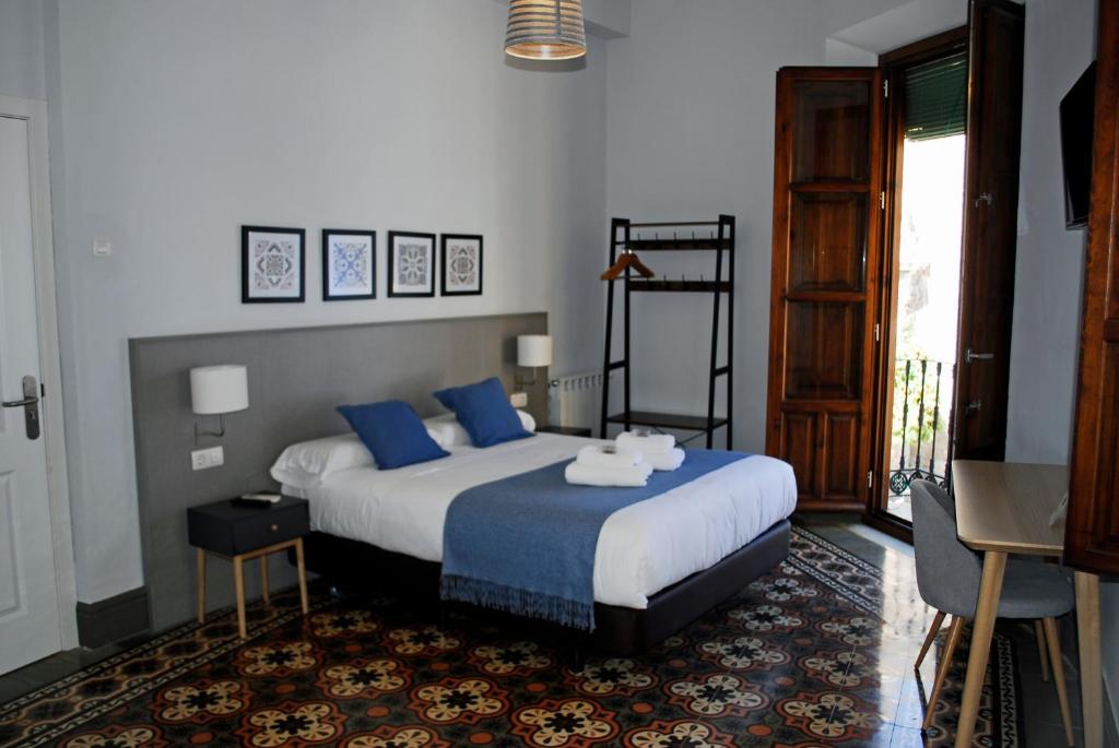 a bedroom with a large bed with blue pillows at La Perla Granada Suites in Granada