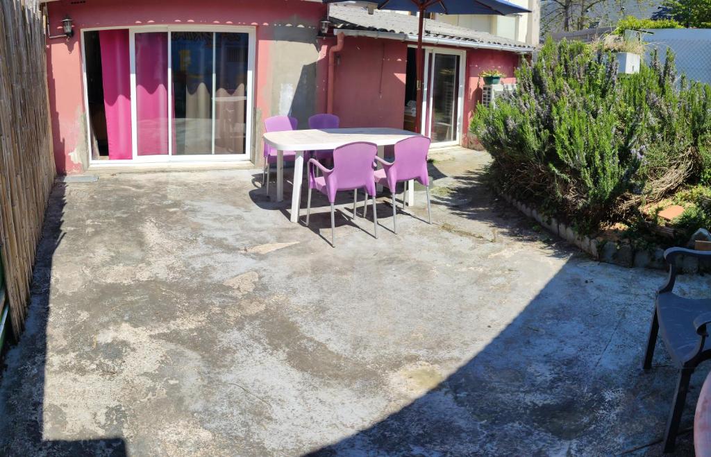 une table et des chaises devant une maison rose dans l'établissement Naciento, à Bagnères-de-Bigorre
