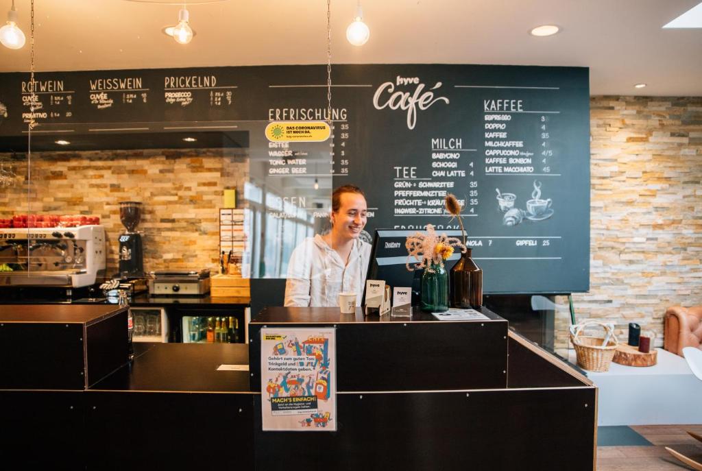 um homem atrás do balcão de um café em Hostel by Hyve Basel em Basileia