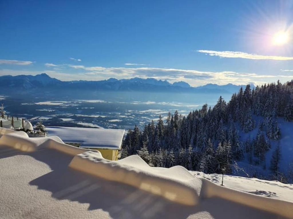 widok na pokrytą śniegiem górę ze słońcem w obiekcie Ferienapartment Kanzelhöhe an der Skipiste w mieście Kanzelhöhe