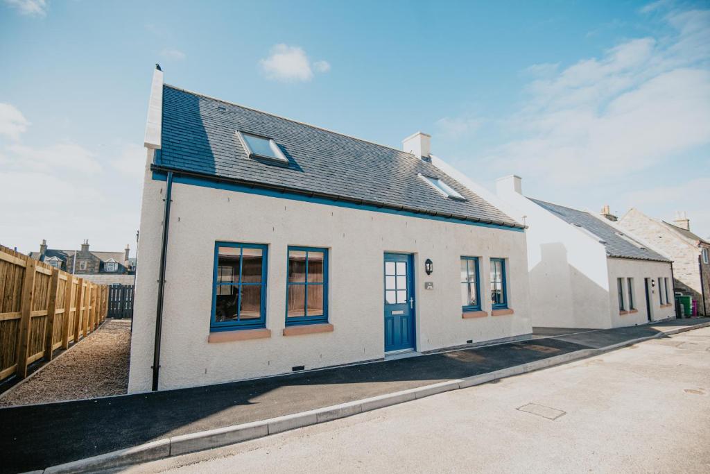 una casa blanca con puertas azules en una calle en The Seafield Arms Hotel Cullen - Self Catering, en Cullen