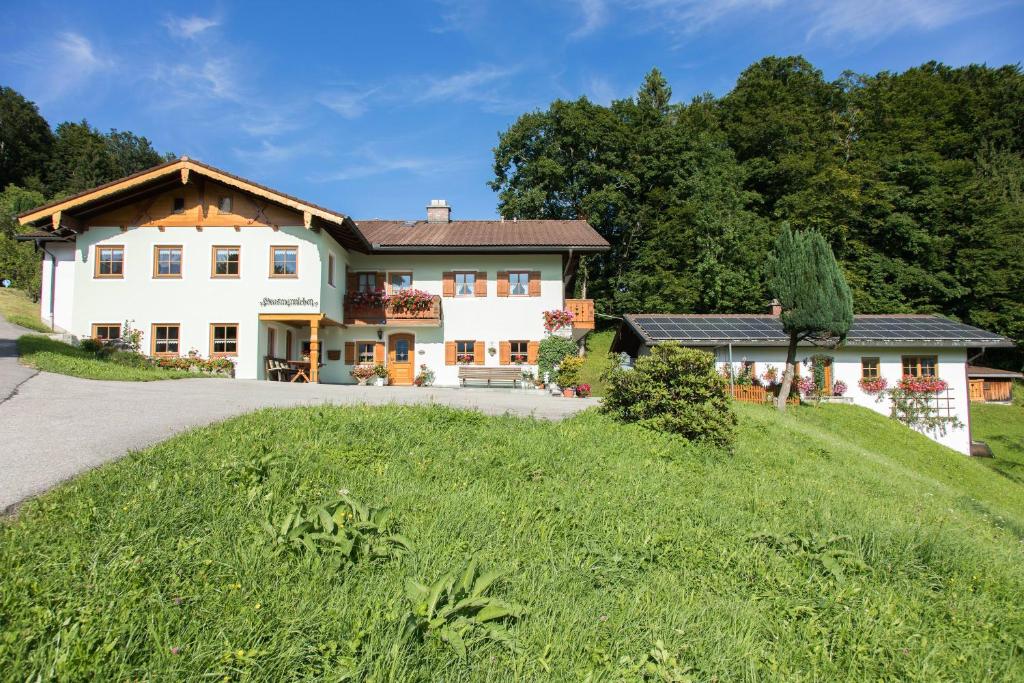 ein großes weißes Haus auf einem grasbewachsenen Hügel in der Unterkunft Ferienwohnung Grasmannlehen in Marktschellenberg