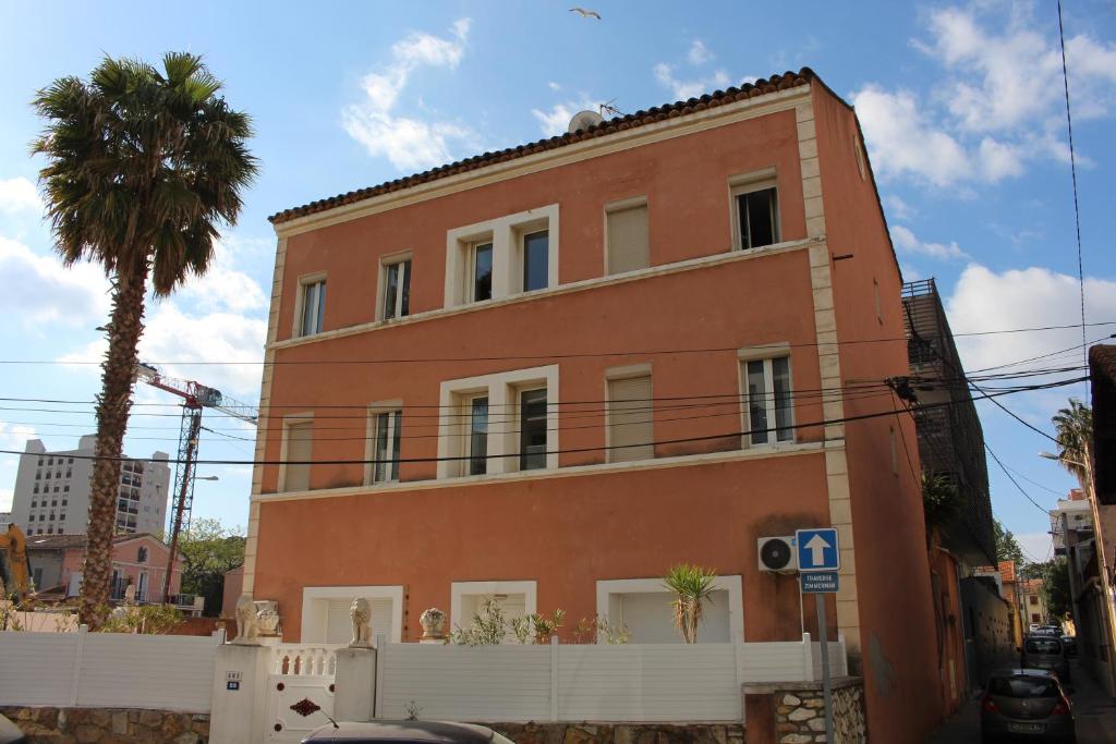 ein hohes rotes Backsteingebäude mit einer Palme in der Unterkunft Residence Enzo Paradise in La Seyne-sur-Mer