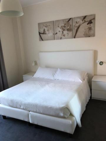 a white bed in a white room with avertisement at Hotel River Palace in Terracina