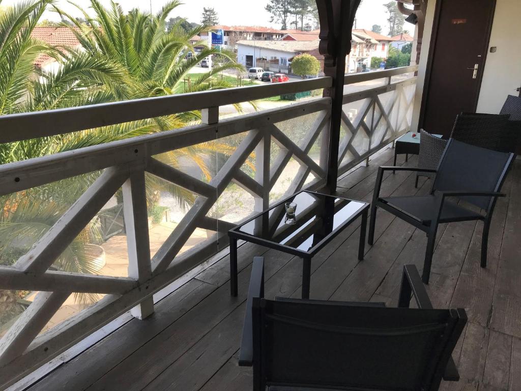 een balkon met stoelen en uitzicht op palmbomen bij Hôtel La Cote d'Argent in Seignosse