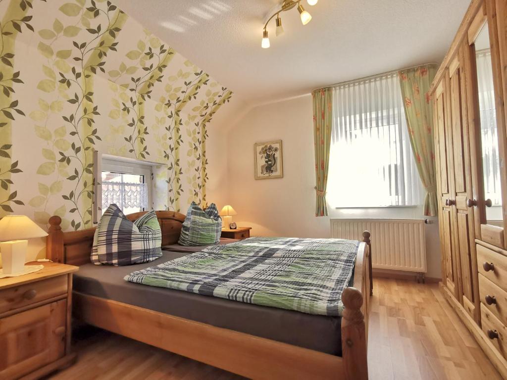 ein Schlafzimmer mit einem Bett mit einer grünen und weißen Decke in der Unterkunft Ferienhaus Scharhörn in Horumersiel