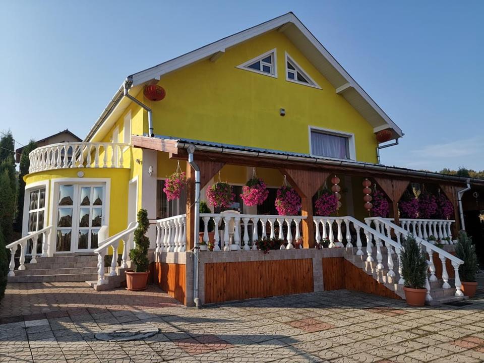 a yellow house with a white fence and flowers at Stars Livezeni in Ivăneşti