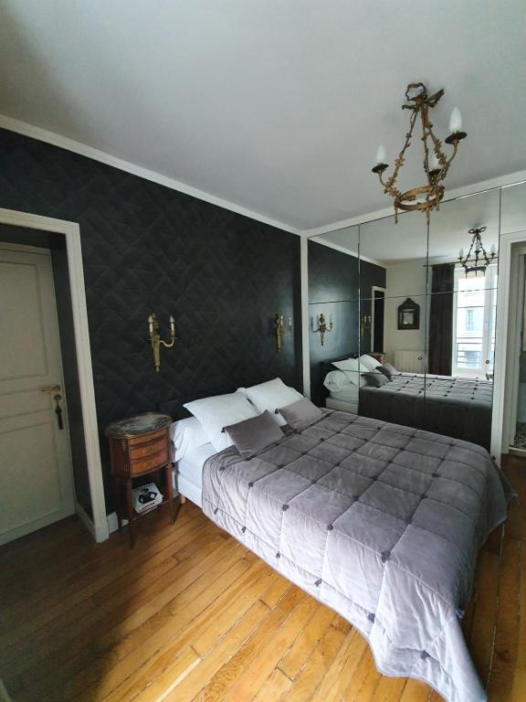 ein Schlafzimmer mit einem großen Bett und einem großen Spiegel in der Unterkunft Chez Pépé Merle - Chambres d'hôtes dans le quartier du Père Lachaise in Paris