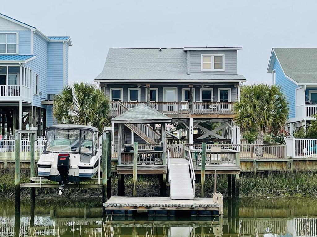 a house with a boat on a dock in the water at Beach Bells Home in Holden Beach