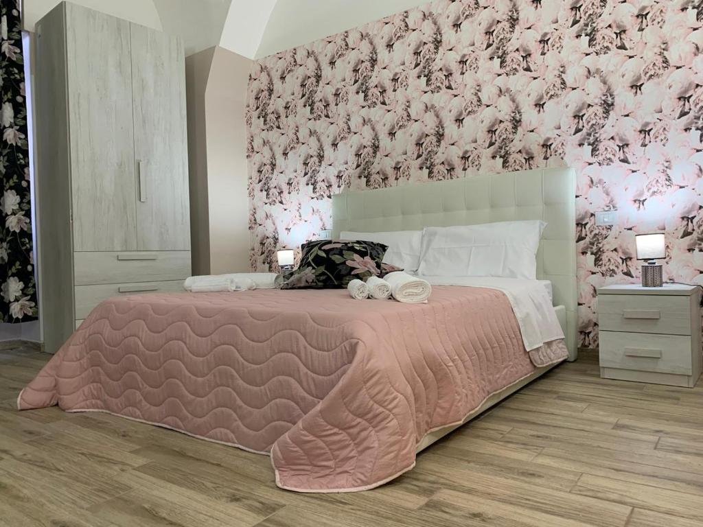 a bedroom with a large bed with a pink wall at The house Porta Garibaldi in Catania