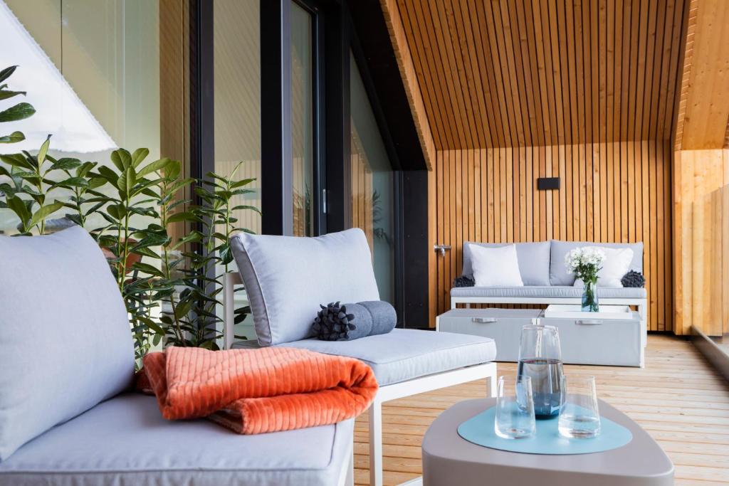 een patio met witte stoelen en een tafel bij HIMMELBLAU - Design Apartment am Mondsee in Mondsee