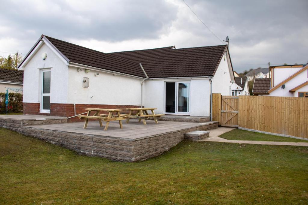 a white house with a picnic table in a yard at Large family Bungalow, parking & Bike Store BPW in Merthyr Tydfil