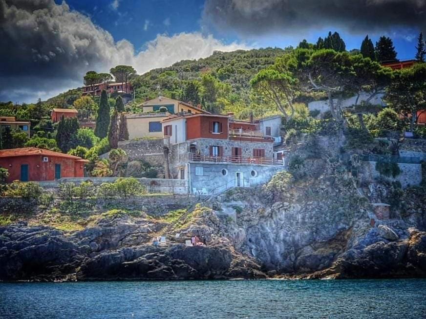 a house on a hill next to the water at VILLA FLORA ARGENTARIO in Porto Santo Stefano