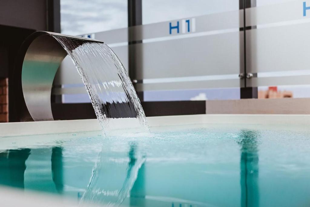 una fuente de agua en una piscina en H1 Apartments Hotel en San Fernando del Valle de Catamarca