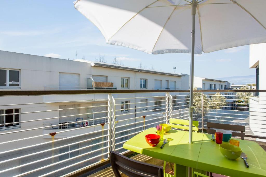 a balcony with a green table and an umbrella at Nice flat with terrace & parking close to beaches in La Rochelle - Welkeys in La Rochelle