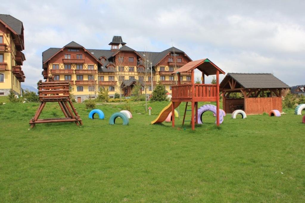 um grupo de equipamentos de recreio em frente a um grande edifício em Apartmán Tatry C3D2 em Veľká Lomnica