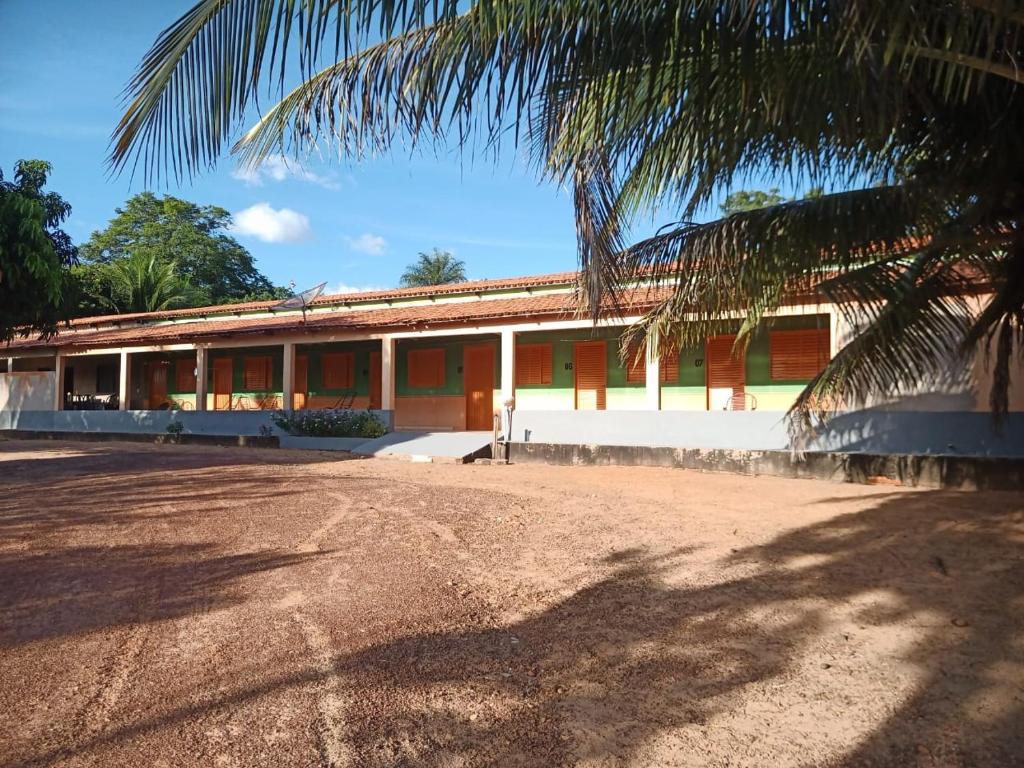 a building with a palm tree in front of it at Pousada do Paulim in São Félix do Tocantins