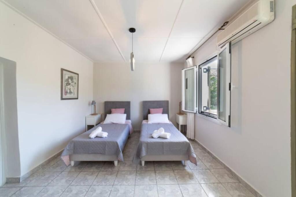 2 łóżka w pokoju z białymi ścianami i oknami w obiekcie STATHI'S COTTAGE w mieście Divarata