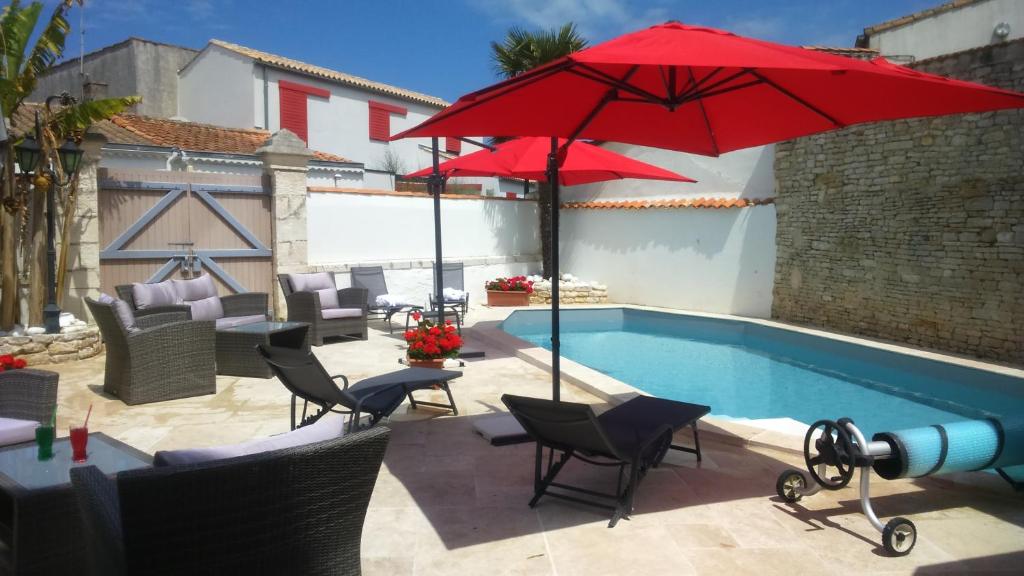 a swimming pool with chairs and a red umbrella at Hotel La Chaudrée in La Brée-les-Bains