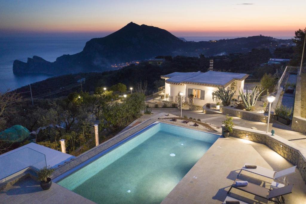 a swimming pool in front of a house with a mountain at Amore Rentals - Villa Ligea in SantʼAgata sui Due Golfi