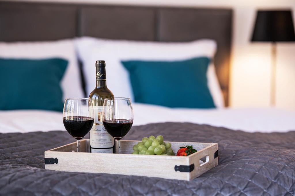 a tray with two glasses of wine and grapes on a bed at Apartament Sedina D211 Nadmorskie Tarasy in Kołobrzeg