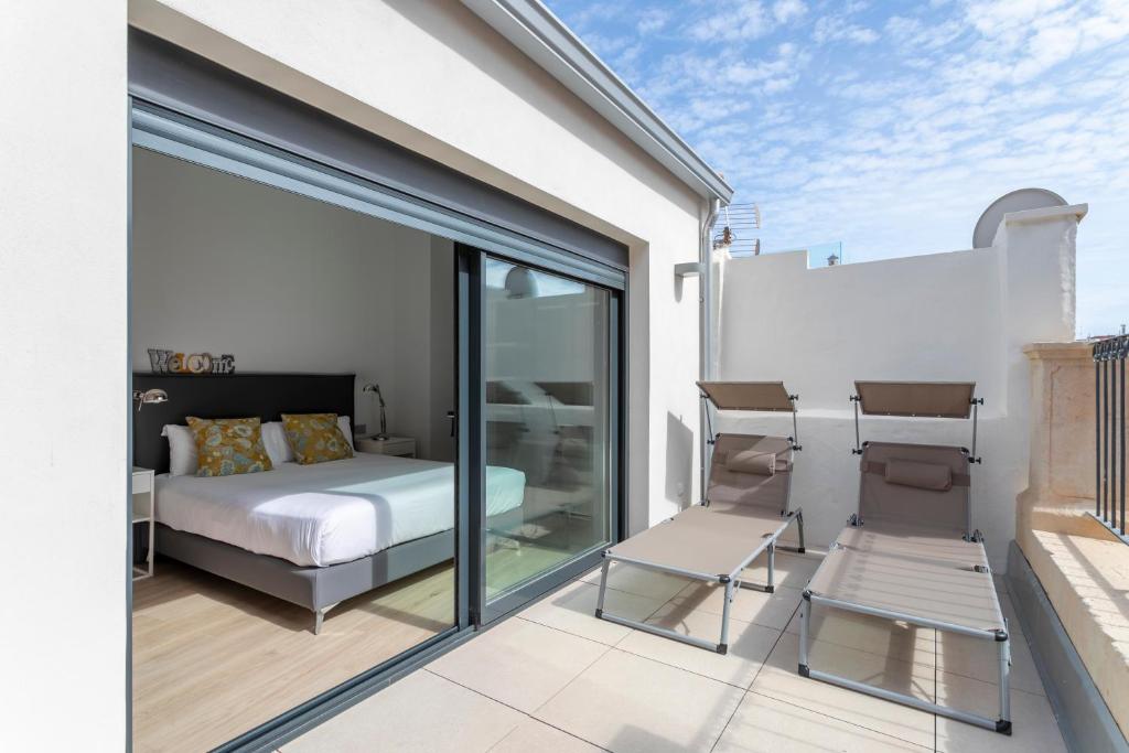 a bedroom with a bed and two chairs on a balcony at Arenal Suites Alicante in Alicante