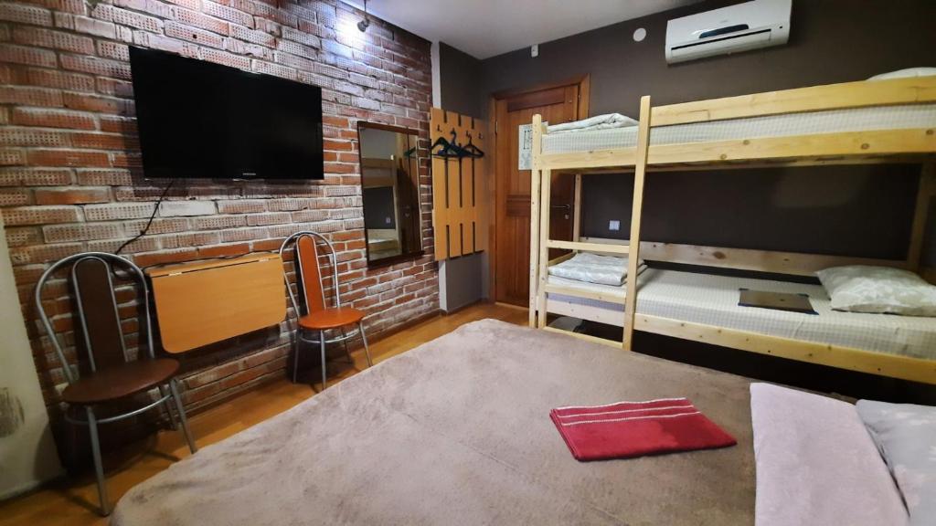 a bedroom with two bunk beds and a flat screen tv at Hostel Happy House в центре in Izhevsk