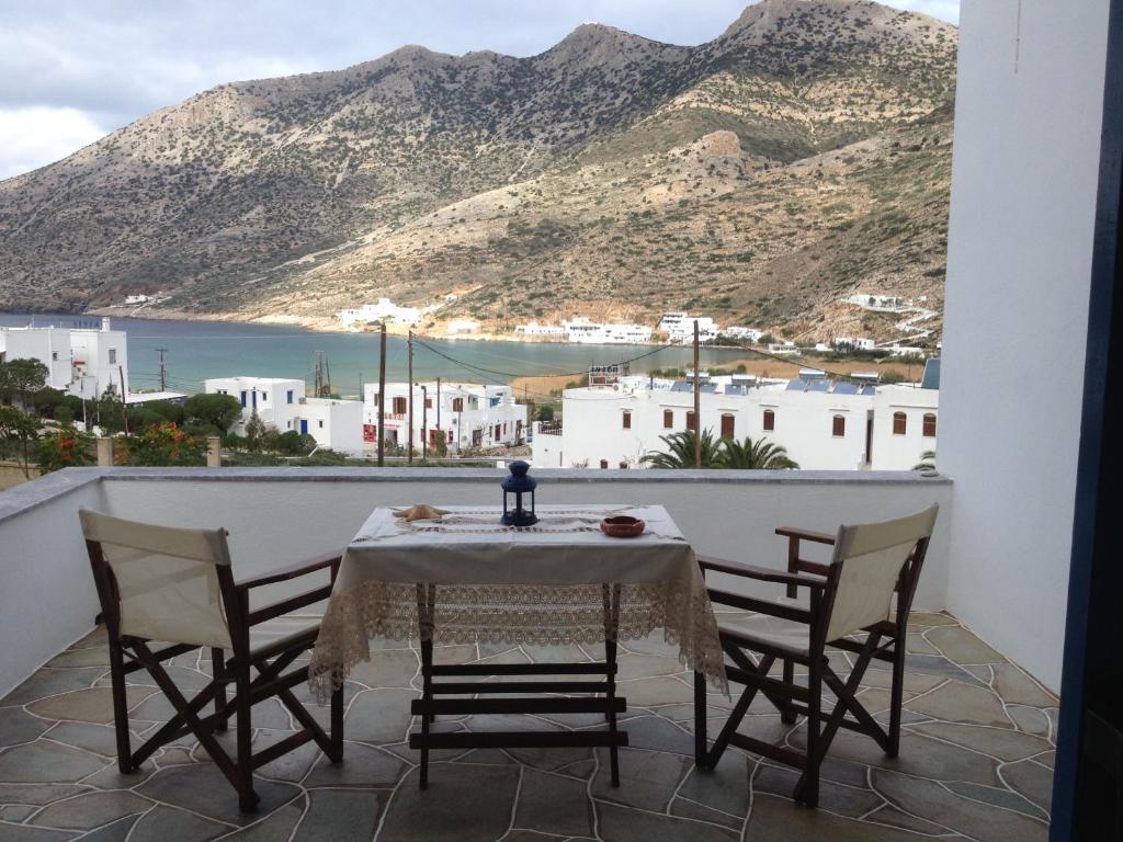 a table on a balcony with a view of the mountains at KIRIKOS ROOMS in Sifnos