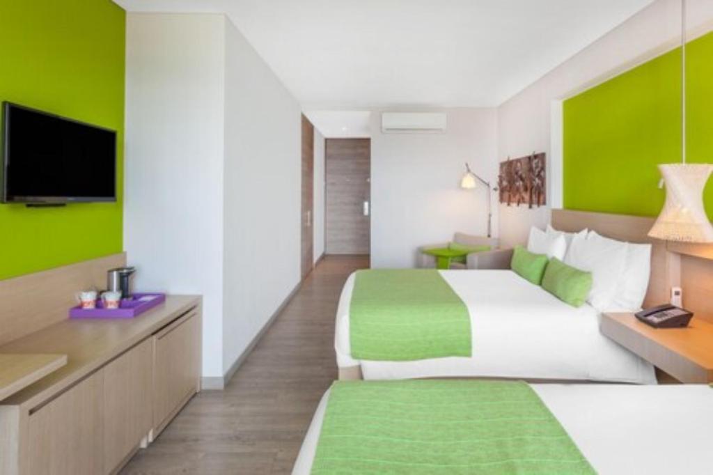 a hotel room with two beds and a flat screen tv at Hotel Bari Bucaramanga in Bucaramanga