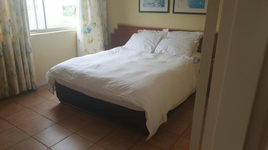 a bed with white sheets and pillows in a bedroom at Kapenta Bay Holiday Resort Port Shepstone unit 12 in Port Shepstone